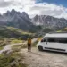 Camper blanca junto a una ruta de montaña con una persona mirando el paisaje