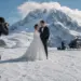 Fotógrafo retrata a una pareja de novios sobre un glaciar, con un helicóptero y montañas nevadas al fondo.