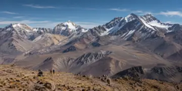 Montañistas y campamento frente a altas cumbres nevadas de los Andes argentinos